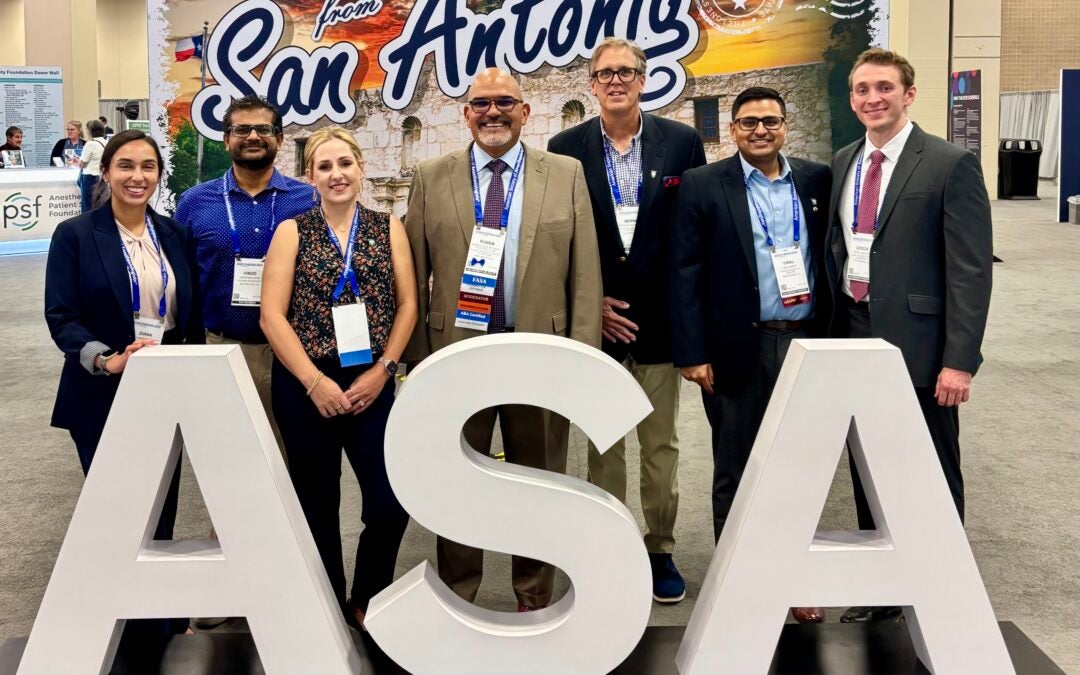 A group of people stand behind large letters of ASA